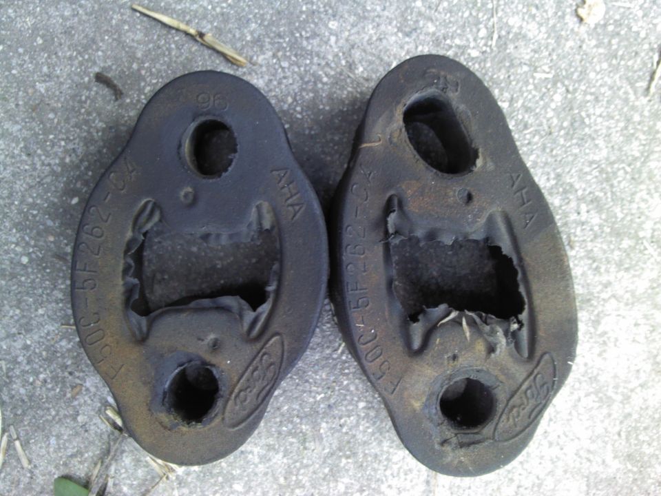 Two black Ford exhaust hangers with part numbers F500-5F262-CA and 96 stamped on them