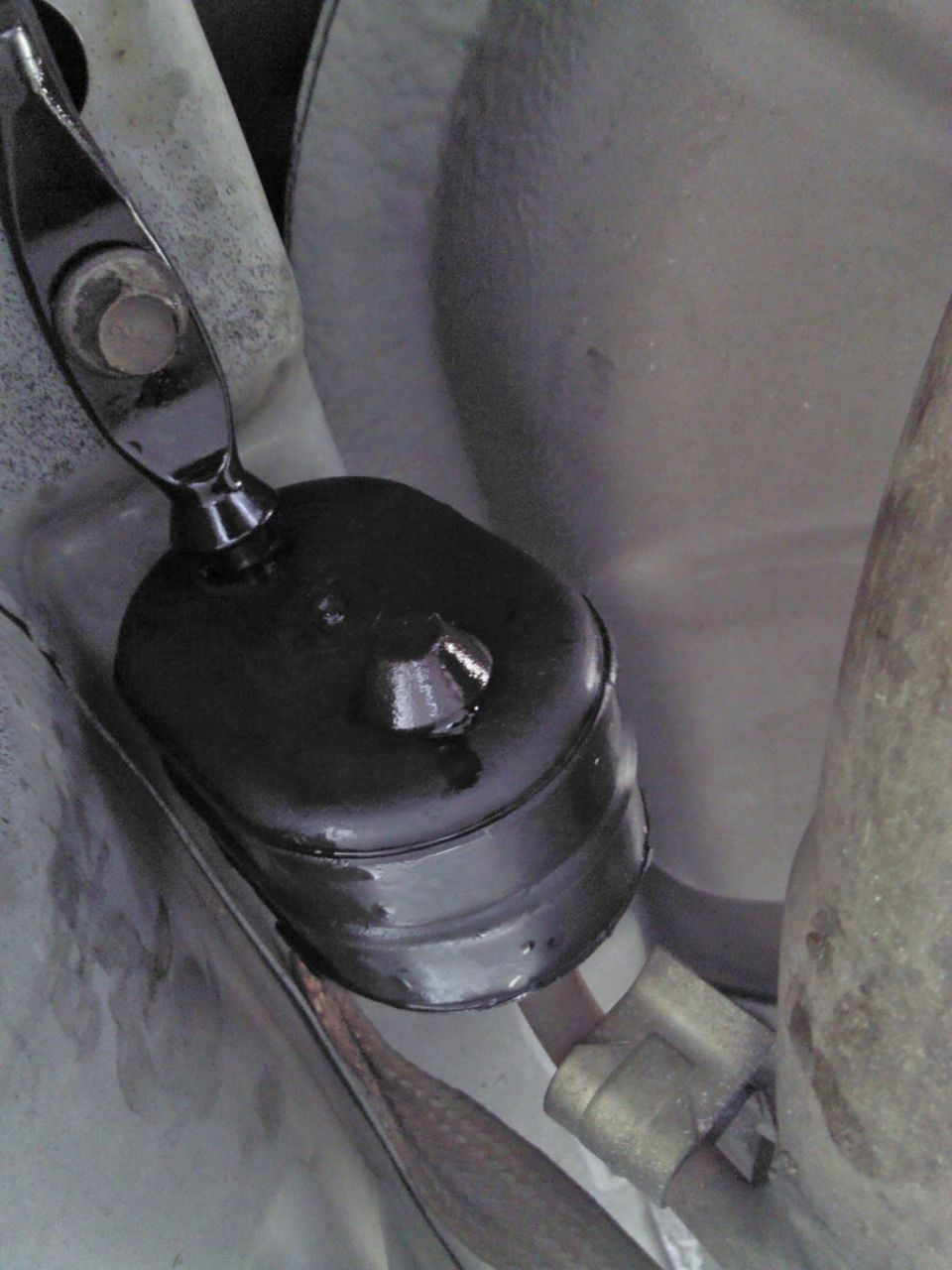 Close-up of a black rubber exhaust hanger bracket attached to a car's undercarriage