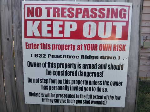 1986 Ford Bronco - A 'No Trespassing Keep Out' sign warns visitors of armed owner and legal consequences.