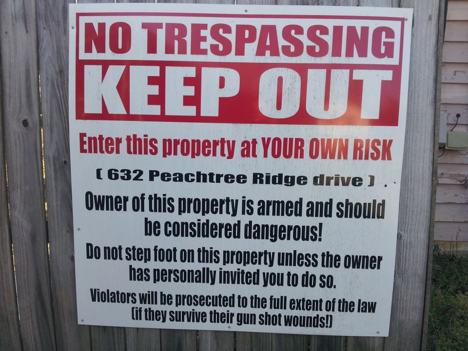 No Trespassing Keep Out sign with address and warning about armed owner