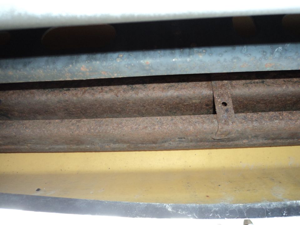 Vehicle underbody with rusty metal pipes and a yellow painted surface