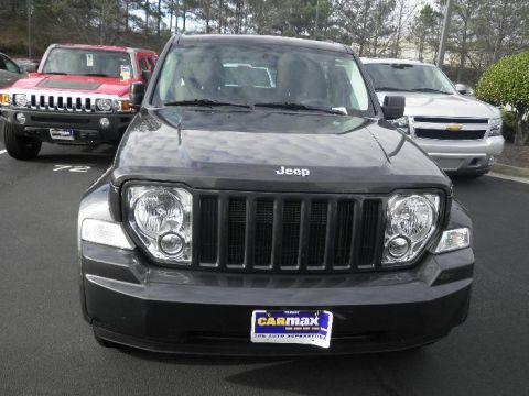2011 Jeep Liberty - A dark gray Jeep Liberty is parked in a lot, with other vehicles visible in the background.