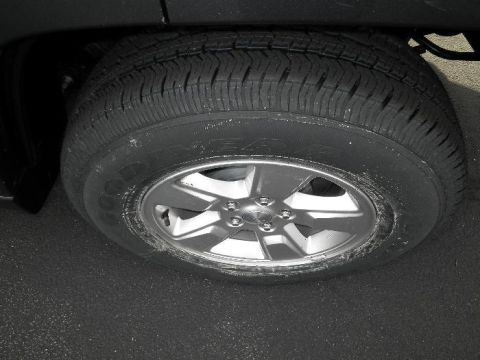 2011 Jeep Liberty - A close-up view of a vehicle's wheel and tire, showing a silver alloy rim with five spokes.