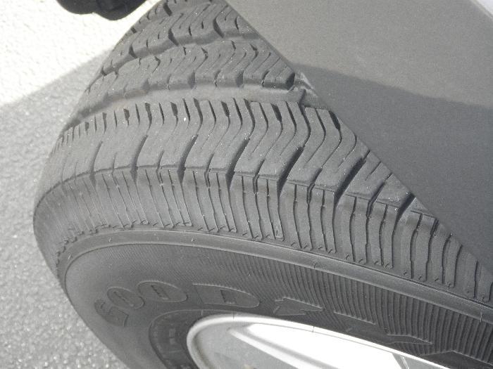 Close-up of a tire with visible tread pattern and part of a silver rim. Text 'GOOD' is partially visible on the tire sidewall