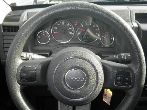 2011 Jeep Liberty - Close-up of the dashboard and steering wheel of a Jeep, the brand's emblem and instrument cluster.