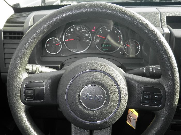 Jeep steering wheel with "Jeep" logo in center, showing dashboard gauges and controls. Matches 2011 Jeep Liberty