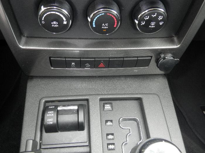 Car interior dashboard with climate controls, hazard lights, 4WD selector, and gear shifter