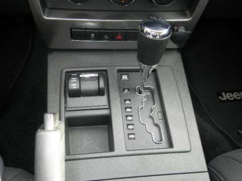 2011 Jeep Liberty - The interior center console of a 2011 Jeep Liberty features a chrome-topped gear shifter and a 4WD selector with '4WD LOW' and '4WD LOCK' o…