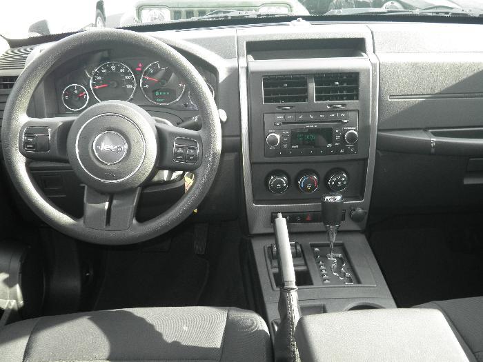 Interior of a Jeep Liberty showing steering wheel, dashboard, radio, and center console.