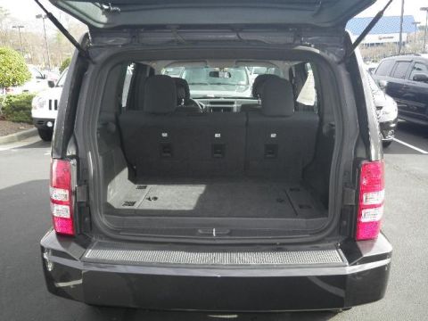 2011 Jeep Liberty - The rear cargo area of a dark SUV is shown with the hatch open, revealing the interior space.