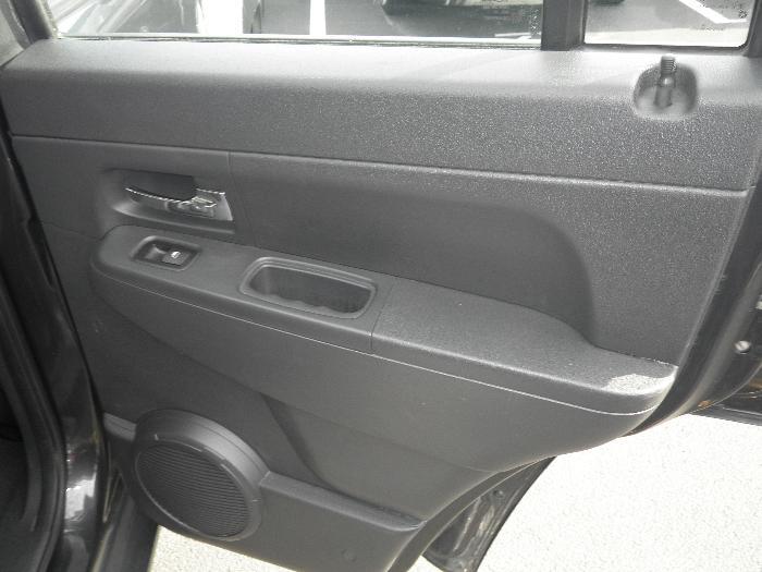 Interior door panel of a dark vehicle with speaker and door handle.