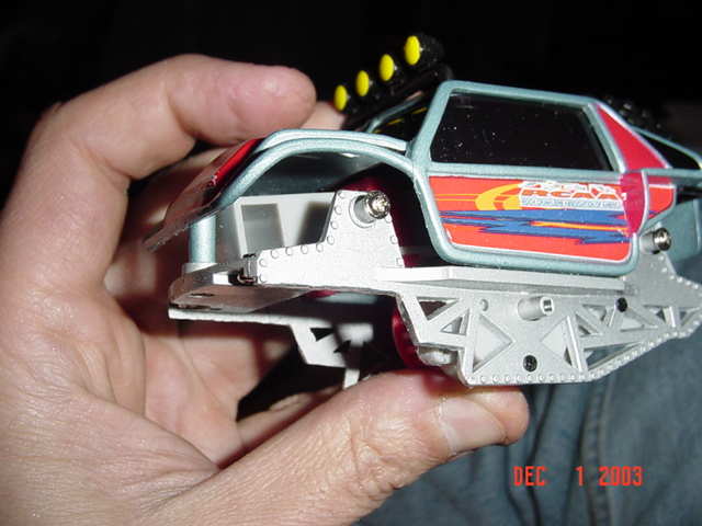 Hand holding a radio-controlled buggy chassis with red and silver body