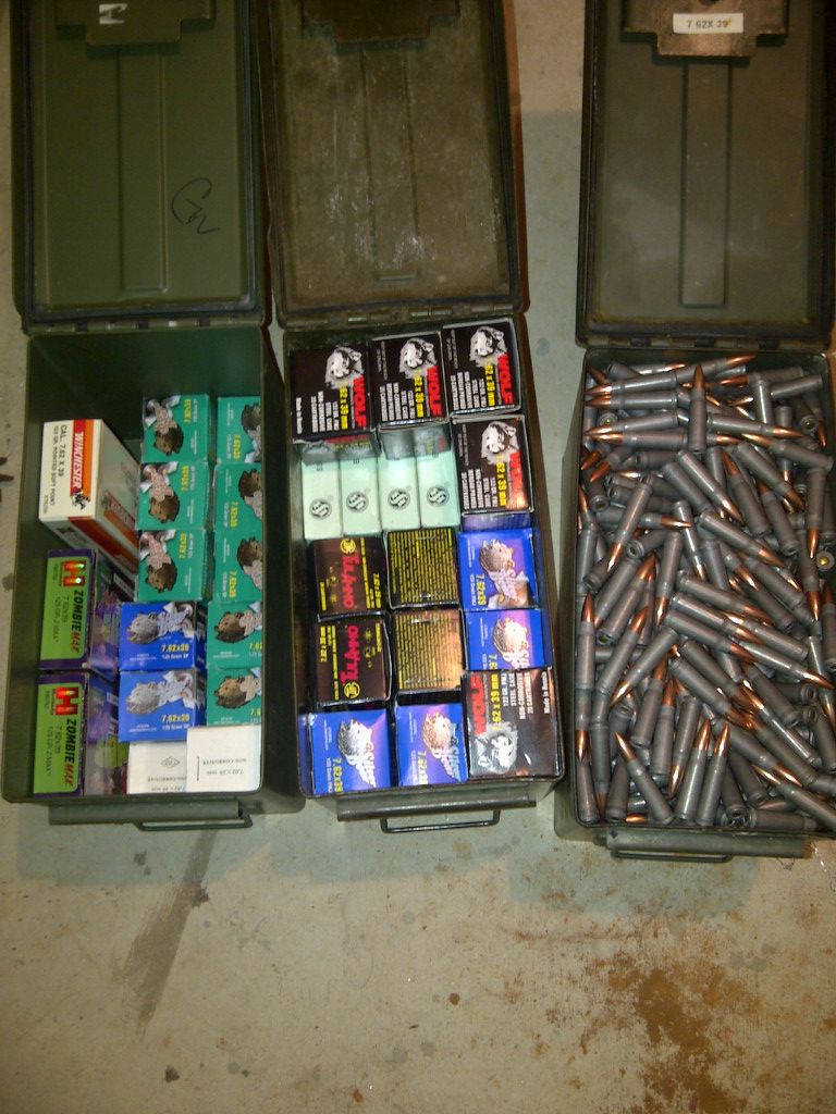 Three open ammo cans filled with various boxes of ammunition and loose cartridges