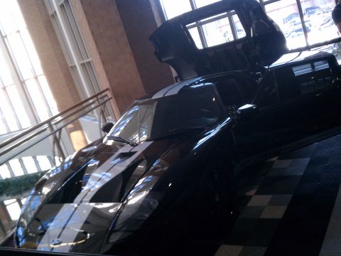 1998 Toyota Camry - A black sports car with white racing stripes is displayed indoors with its gullwing doors open.