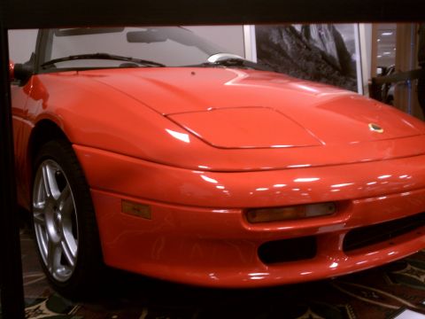 1998 Toyota Camry - A red convertible sports car is shown from the front, a Lotus emblem on the hood.