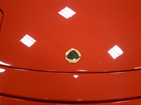 1998 Toyota Camry - Close-up of a Lotus emblem on the hood of a red car.