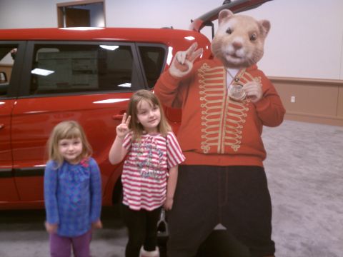 1998 Toyota Camry - Two young girls pose with a mascot costume in front of a red car at what appears to be a dealership or auto show.