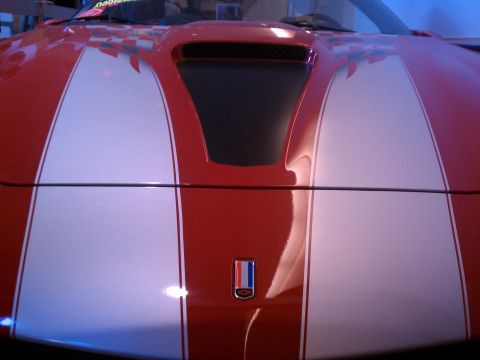 1998 Toyota Camry - Close-up of a red car's hood white racing stripes and a prominent black air scoop.