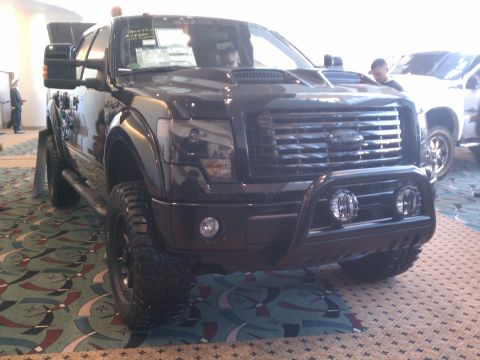1998 Toyota Camry - A modified black Ford F-150 truck is displayed indoors with a white truck visible in the background.