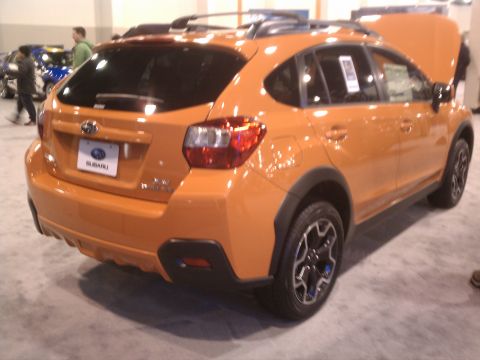1998 Toyota Camry - An orange Subaru crossover is displayed with its hood open, likely at an auto show.