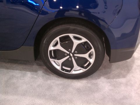 1998 Toyota Camry - Close-up of a blue car's rear wheel and fender, showing a distinctive rim design.