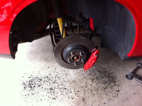 2010 Dodge Challenger - Close-up of a red car's front brake assembly, showing the caliper and rotor.