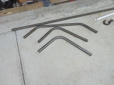 1990 Ford Bronco - Several bent metal tubes and a hook lie on a concrete surface, possibly for a custom build.