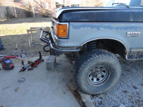 1990 Ford Bronco - The front quarter panel of a 1990 Ford Bronco shows a custom bumper and welding gear on the ground.