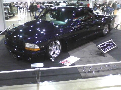 2003 Ford Crown Victoria - A custom pickup truck is displayed indoors with a "Lowkota" sign and other items on a mat.