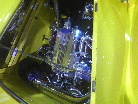 2003 Ford Crown Victoria - The engine bay of a yellow vehicle displays custom chrome parts and blue accents.