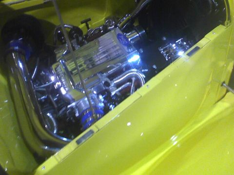 2003 Ford Crown Victoria - Customized engine bay with polished chrome and blue hoses, set against a bright yellow exterior.
