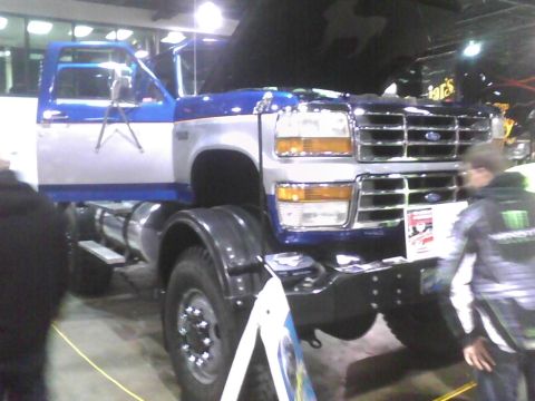 2003 Ford Crown Victoria - A blue and silver Ford F-Series truck is displayed indoors, a prominent chrome grille and large tires.