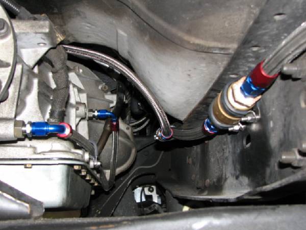 underbody view of transmission and braided fuel lines with blue and red fittings