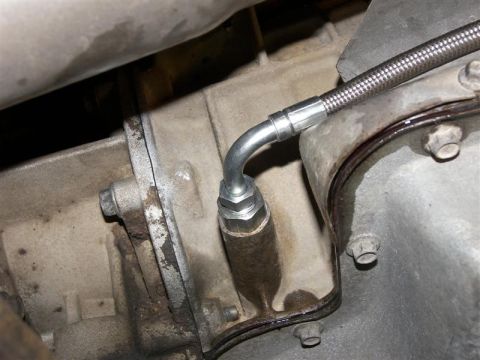 1990 Ford Bronco - Close-up view of a transmission fluid line connection on a vehicle's mechanical component.