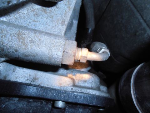 1990 Ford Bronco - Close-up of a hydraulic line connection on an engine block.