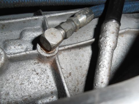 1990 Ford Bronco - Close-up view of a transmission fluid line connection point on a metal housing.