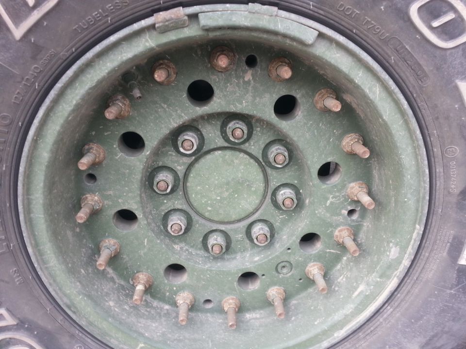 Green military truck wheel with multiple lug nuts and studs