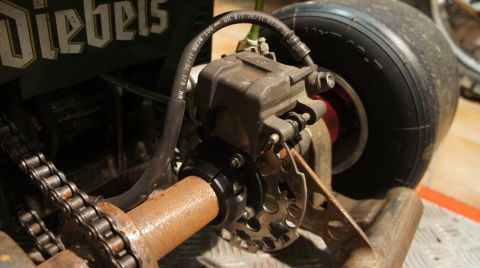 1973 Ford Ranchero - Close-up of a go-kart's rear axle assembly, showing the brake caliper, disc, and chain.
