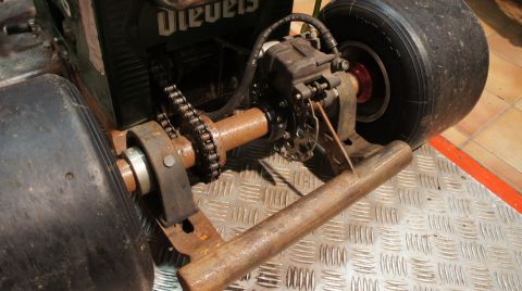 1973 Ford Ranchero - Close-up view of the rear axle assembly and wheel of a go-kart, showing the brake system and drive chain. Text from a watermark is visible.