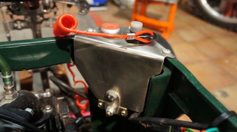 1973 Ford Ranchero - Close-up view of an engine bay component an orange cap and a protective metal cover.