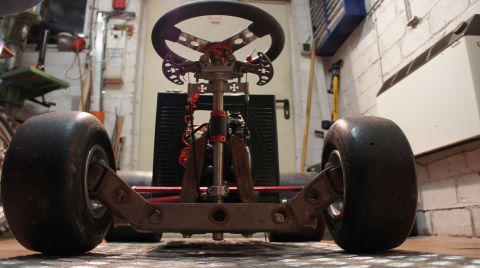 1973 Ford Ranchero - Low-angle view of a go-kart's front axle, steering column, and large tires, suggesting a custom build or racing setup.