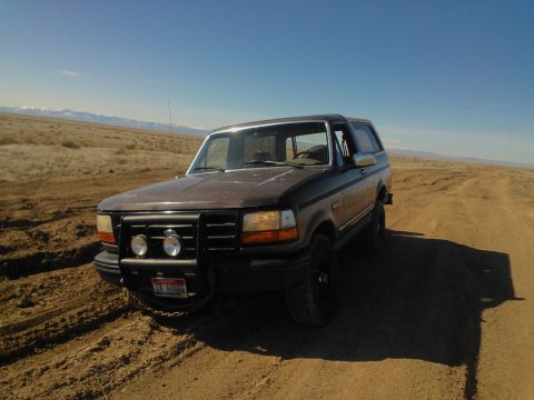 1992 Ford Bronco - This 1992 Ford Bronco is parked on a dirt track in a desert-like environment under a clear blue sky.