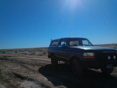1992 Ford Bronco - This Ford Bronco is parked on a dusty, off-road trail with a clear blue sky overhead.