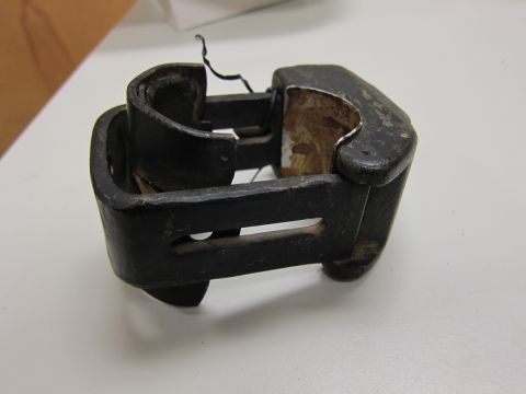 2001 Ford Crown Victoria - A close-up view of a worn, black metal siren mounting bracket, likely from a police vehicle.
