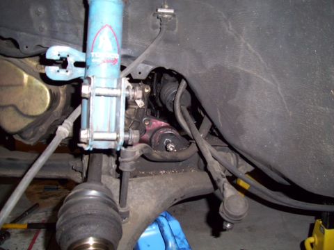 1995 Ford Probe - Close-up view of a vehicle's front suspension system, showing a blue shock absorber and various mechanical parts.