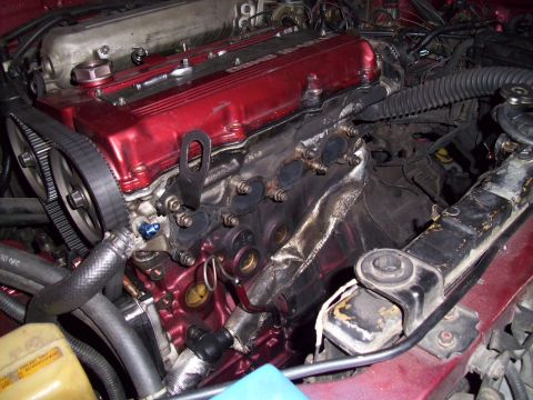 1995 Ford Probe - The engine bay shows a red valve cover and exposed exhaust manifold with heat shielding.