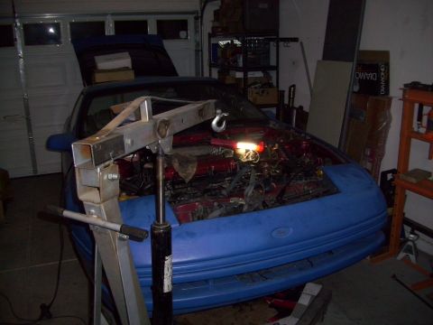 1995 Ford Probe - A blue 1995 Ford Probe is in a garage with its hood open and engine exposed, ready for work with an engine hoist positioned over it.