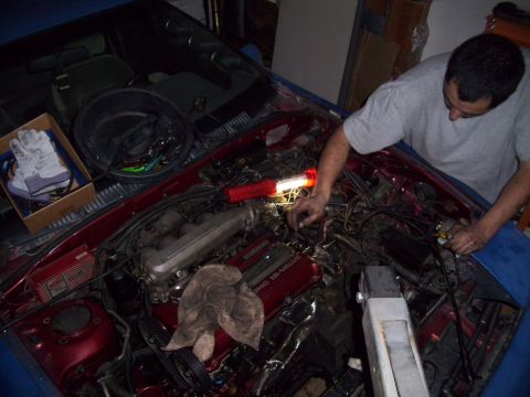 1995 Ford Probe - A mechanic works on the engine of a red car, with tools and gloves laid out.