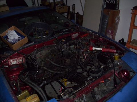 1995 Ford Probe - The engine bay of a red vehicle is shown with various tools and parts scattered around, suggesting maintenance or repair work is in progres…