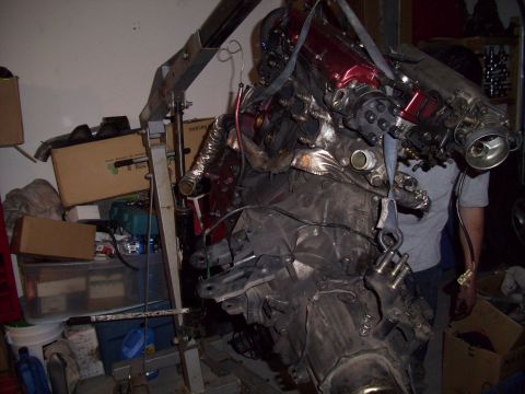 1995 Ford Probe - Engine assembly being worked on, suspended by an engine hoist in a cluttered garage setting.